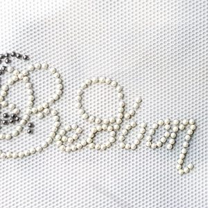 Bedoon Essm white beads with sunflower logo