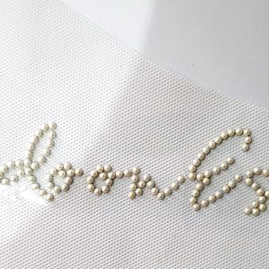 Bedoon Essm white beads with brown, red, purple logo